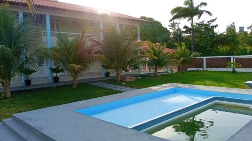 a pool in front of a house with palm trees at Casa do Lago Salinópolis in Salinópolis
