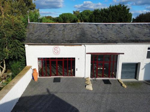 a small white building with red doors and a roof at maison chaleureuse ,avec piscine, spa, Futuroscope in Jaunay-Marigny