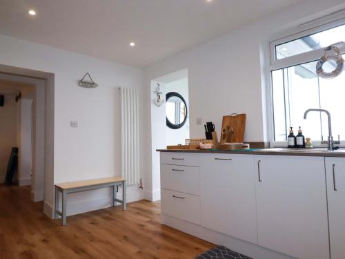 a kitchen with white cabinets and a sink and a window at Ocean Edge in Sennen Cove