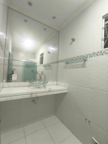 a white bathroom with a sink and a mirror at Varanda das araras in Manaus