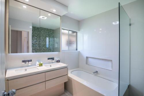 y baño con lavabo, bañera y espejo. en Offshore Noosa Resort en Noosaville