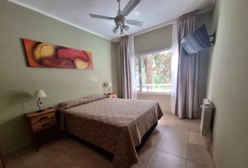 a bedroom with a bed with a ceiling fan and a window at Apart Hotel Naga Huel in Sierra de la Ventana