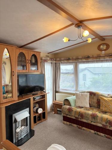 a living room with a couch and a fireplace at Seaside Escape 2-Bed Caravan at Seven Bays Park in Saint Merryn