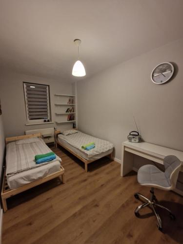 a room with two beds and a desk and a chair at Apartament Jana in Warsaw