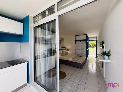 Un dormitorio con una cama y una puerta corrediza de vidrio. en Pause tropicale, en Le Diamant
