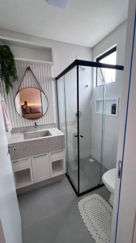 een badkamer met douche, wastafel en spiegel bij Cambllis in Bombinhas