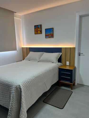 een slaapkamer met een groot bed en een nachtkastje bij Cambllis in Bombinhas