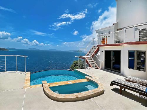 a swimming pool on the side of a house with the ocean at Villa Vista Oceanfront 4BR - Infinity Pool - Views in Enighed