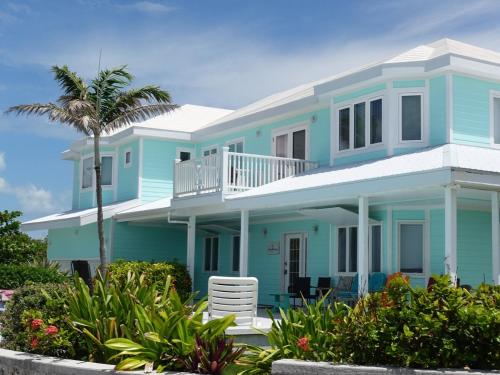 a blue house with a palm tree in front of it at Bahamian Rhapsody of Hopetown, Elbow Cay, Abaco,BA 