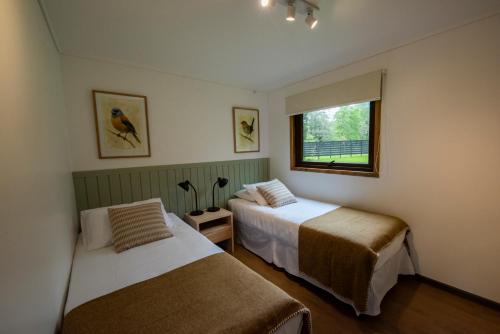 ein Schlafzimmer mit zwei Betten und einem Fenster in der Unterkunft Cabañas Parque Futangue in Lago Ranco