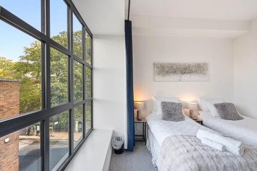 zwei Betten in einem Zimmer mit großen Fenstern in der Unterkunft Castle View By Ginger & Gold Luxury Norwich Apt in Norwich