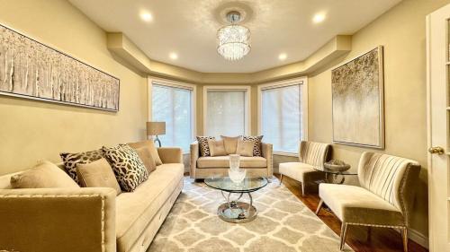 ein Wohnzimmer mit Sofa, Stühlen und einem Tisch in der Unterkunft Designer 4BR Retreat, Luxe Living & Family-Friendly Fun in Mississauga