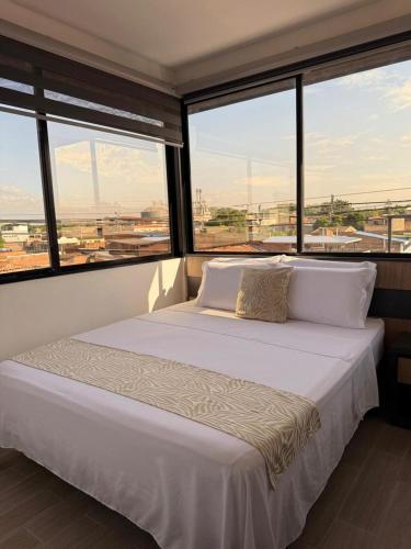 a large bed in a room with large windows at GRAND HOTEL JAMUNDI in Jamundí