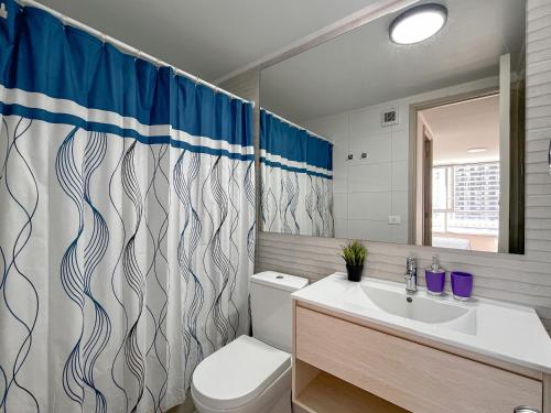 Un baño con inodoro, lavabo y cortina de ducha. en Loica Host - Smart, en Santiago