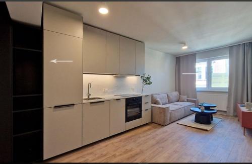 a kitchen with white cabinets and a living room at Apartament Podniebny z Windą in Kluczbork