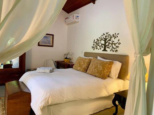 una camera da letto con un letto con lenzuola bianche e cuscini dorati di Vila Maria - Linda Casa de Campo a Rio de Janeiro