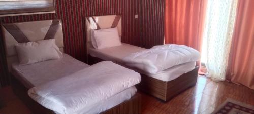a room with two twin beds with white sheets at Wadi Rum Sand moon Camp &Tour in Wadi Rum