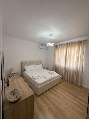 a white bedroom with a bed and a wooden floor at Estel Apartament in Tirana