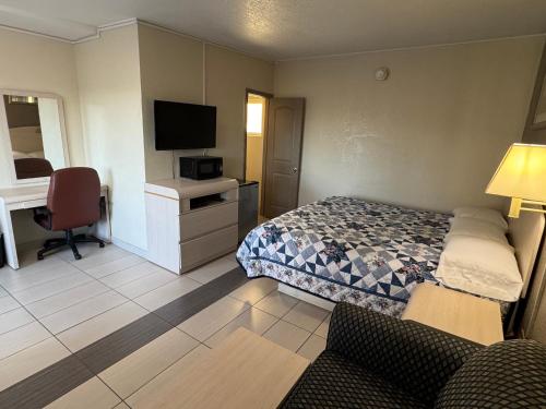 a bedroom with a bed and a desk with a television at American Inn in Cocoa