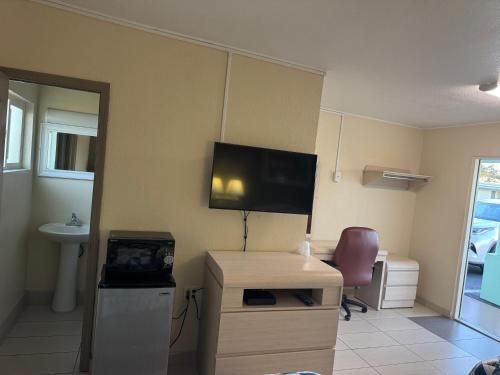 a room with a television and a desk with a chair at American Inn in Cocoa