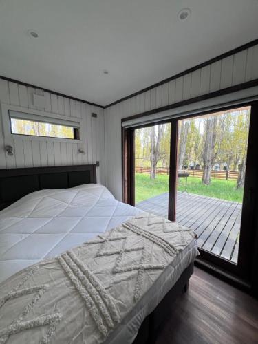 a bedroom with a bed and a large window at Cabaña entre alamos in Coihaique