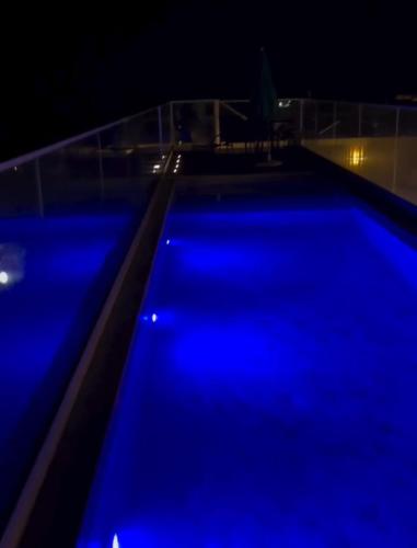 een zwembad verlicht in de nacht met blauwe lichten bij Ap Villa Toscana in Ilhéus