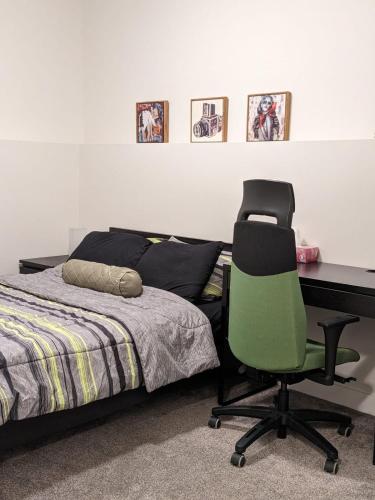 ein Schlafzimmer mit einem Schreibtisch und einem grünen Stuhl neben einem Bett in der Unterkunft MegaVille in Saskatoon