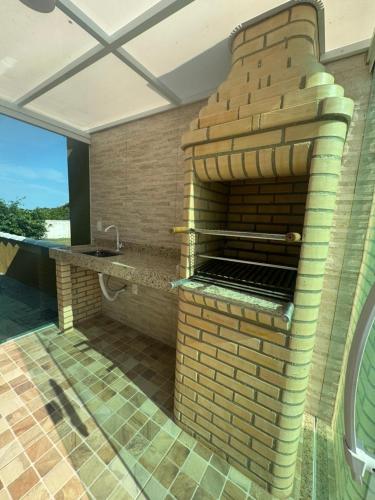 an outdoor kitchen with a brick wall and a sink at Faith Home 4 in Arraial do Cabo