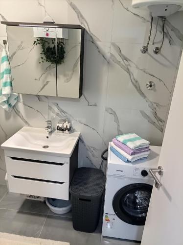 a bathroom with a sink and a washing machine at INKOGNITO Centar 39 in Brčko