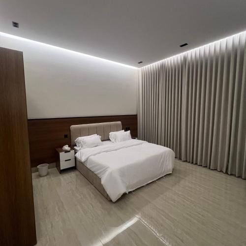 1 dormitorio con 1 cama blanca grande y cortinas en سويت ضيافة البرج, en Al Kharj