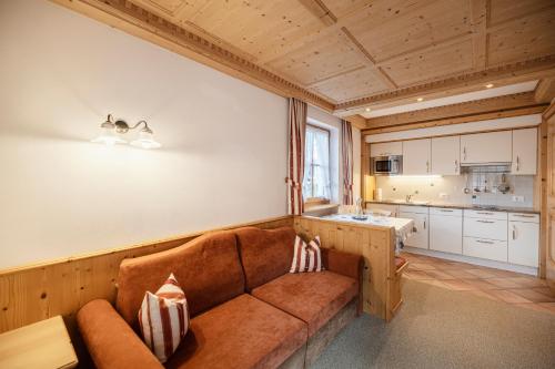 een woonkamer met een bank en een keuken bij Chalet Bel Plan in Ortisei