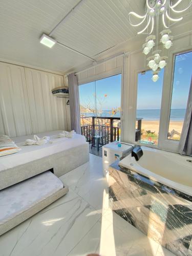 a bedroom with two beds and a bathtub and the ocean at Pousada São Miguel Beach Beira Mar in Penha