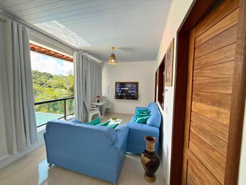 een woonkamer met twee blauwe stoelen en een raam bij MHV Milagres - Casa Lar do Marceneiro, Casa reservada e privativa a poucos metros da Praia do Marceneiro e da Capela in Passo de Camarajibe