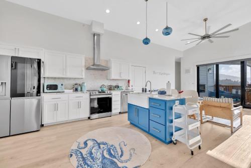 a kitchen with white cabinets and a blue island at Deja View - Ocean View Neskowin Luxury in Neskowin