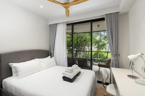 een slaapkamer met een bed, een bureau en een raam bij Laguna beachside residences by My home Phuket in Bang Tao Beach