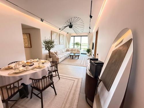 a dining room with a table and chairs and a living room at Golf view living by FlamingoAmber Dubai in Ajman