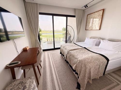 a hotel room with a bed and a desk and a window at Golf view living by FlamingoAmber Dubai in Ajman