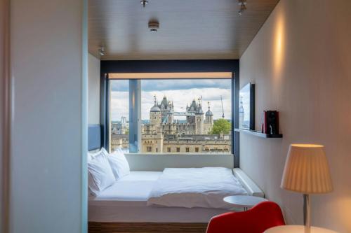 a bed in a room with a large window at citizenM Tower of London in London