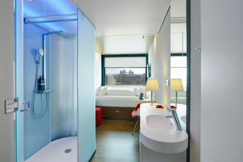 a bathroom with a shower and a sink and a tub at citizenM Tower of London in London