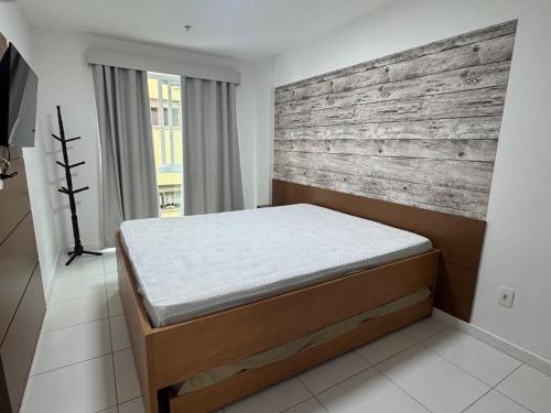 ein Bett in einem Zimmer mit einer Holzwand in der Unterkunft MANDAI - Cabo Frio - RJ in Cabo Frio