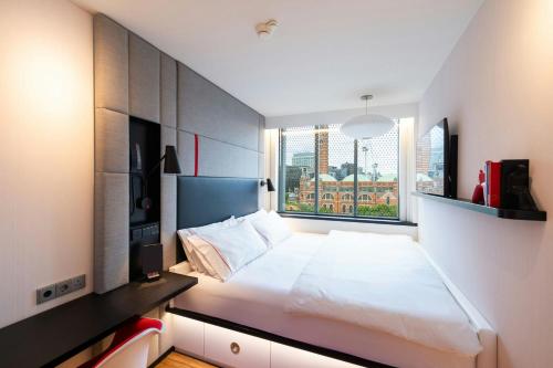 a bedroom with a bed and a large window at citizenM London Victoria Station in London