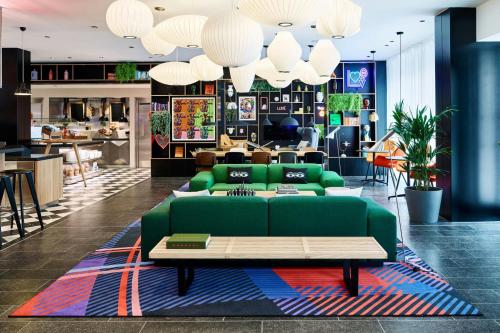 a living room with a green couch and a table at citizenM London Victoria Station in London