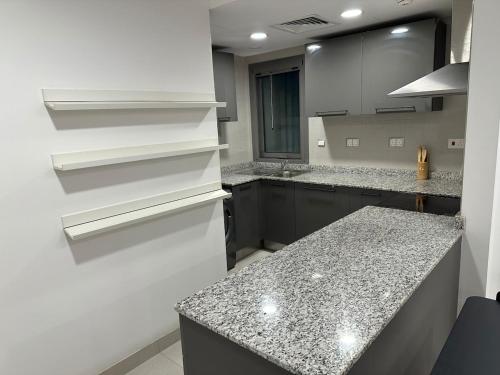 a kitchen with white cabinets and granite counter tops at Central Bliss Apartment in Muscat