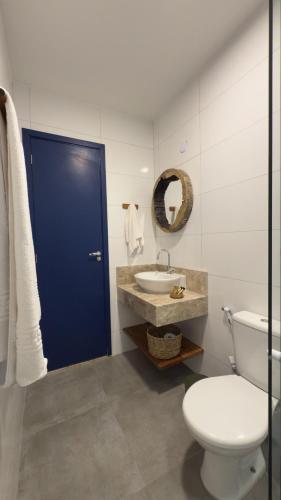 a bathroom with a blue door and a toilet and a sink at Boulevard Pousada Boutique in Guaramiranga