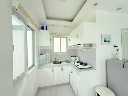 Una cocina blanca con gabinetes blancos y un fregadero. en Chateau Du Soleil, en San Vicente