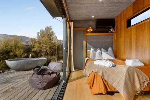 a bedroom with a tub and a bed on a deck at Luxury Container and Cabin with Outdoor Bath in Wanaka
