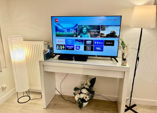 a computer monitor on a white desk with a television on it at Neuf et lumineux 2min Gare - 20min Paris in Maisons-Laffitte