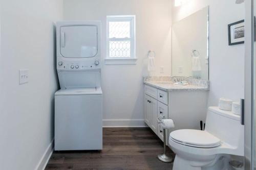 a white bathroom with a toilet and a sink at Charming Old Town Loft, nestled in the Heart of Historic Bluffton, SC in Bluffton