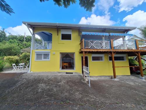 a yellow house with a balcony on top of it at Gite DANGIEN in Vieux-Habitants