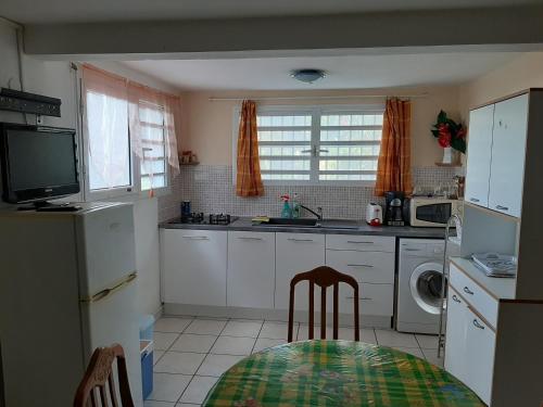 a kitchen with white cabinets and a table and a television at Gite DANGIEN in Vieux-Habitants